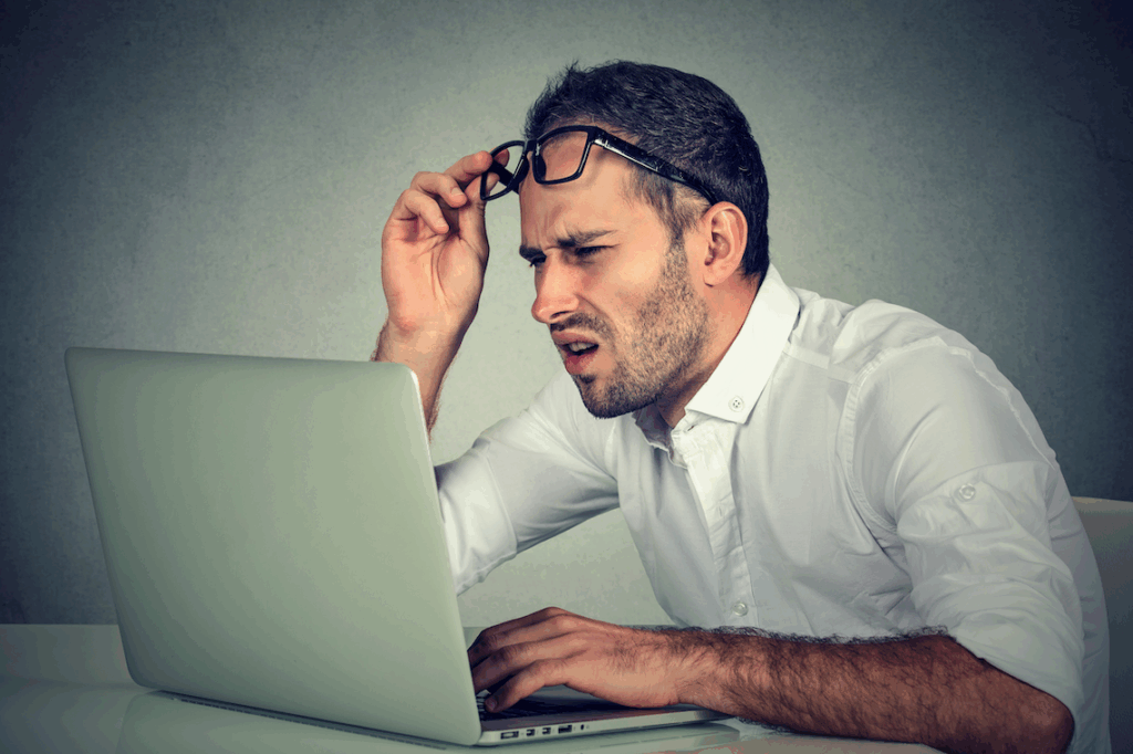 Confused man reading the news on his computer can't believe what he's seeing