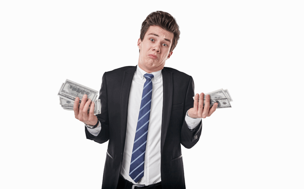 Businessman holding stacks of money and shrugging
