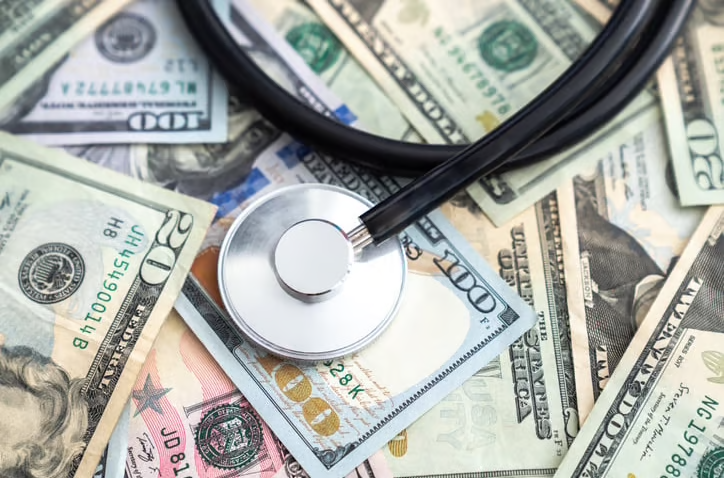 A stethoscope sitting on a pile of cash