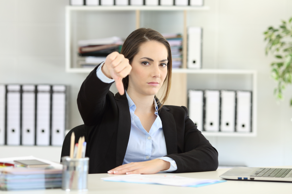 Woman at a desk showing thumbs down
